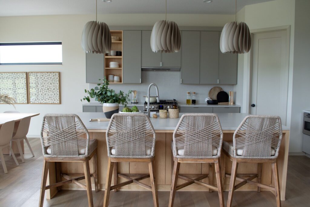 Japandi style kitchen with architectural pendants and woven counterstools. 